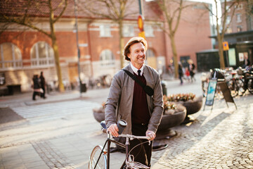 Mature man pushing his bicycle in the city and having coffee