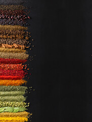 Large collection spices and herbs on background of  black table. Colorful condiments with empty space for text or label.