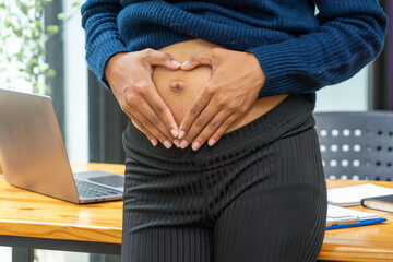 Young latin woman pregnant smiling confident touching tummy working at office