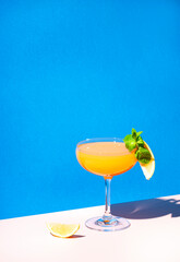 Paddington alcoholic cocktail drink with rum, yellow liquor, grapefruit and lemon juice, marmalade and absinthe, summer blue bright background, hard light and shadows