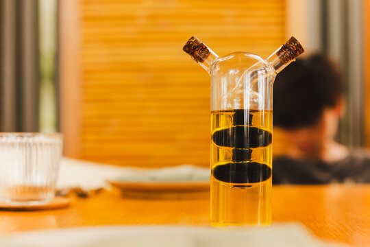 A glass bottle with olive oil and balsamic vinegar on dinner table.