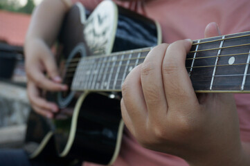 Young woman playing guitar at home.