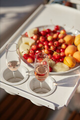 Juicy bright fruits apricot, cherry, melon, two glasses of wine - on the boat tray of the yacht. A warm sunny summer day. Relaxation and rest. Romantic date on a yacht, ship, boat.