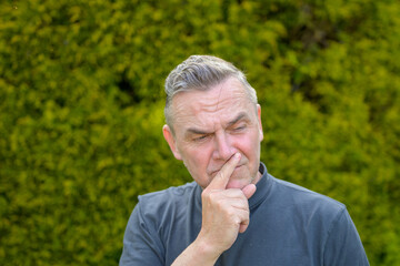 Portrait of a middle-aged man with gray hair standing in the garden