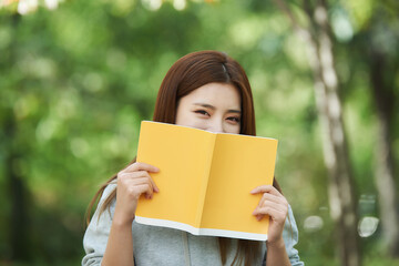 A beautiful woman, a college student, reading in a forest park