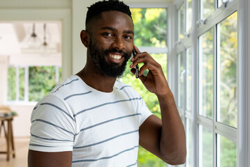 Portrait of happy african american man talking on smartphone at home