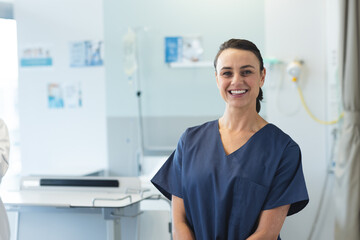 Portrait of happy caucasian female doctor wearing blue scrubs at hospital, copy space