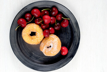 Dish with delicious doughnuts and cherries
