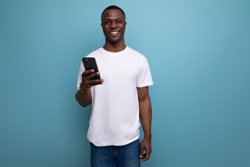 well-groomed 30s african man with short haircut in white t-shirt with smartphone