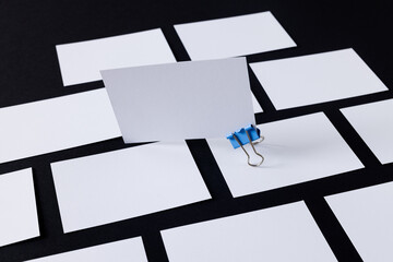 White business cards with paperclip and copy space on black background