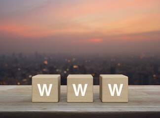 WWW letter on wood block cubes on wooden table over blur of cityscape on warm light sundown, Searching system and internet concept