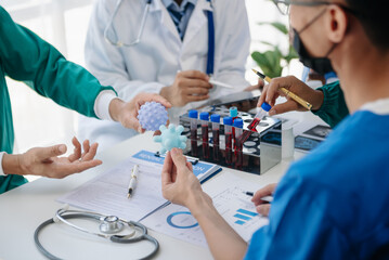 Medical team having a meeting with doctors in white lab coats and surgical scrubs seated at a table...