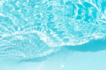 Obraz premium Blue water with ripples on the surface. Defocus blurred transparent blue colored clear calm water surface texture with splashes and bubbles. Water waves with shining pattern texture background.