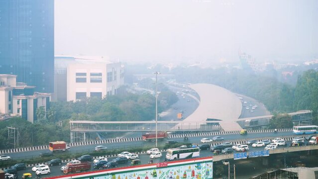 gurgaon cityscape with traffic cars bikes on elevated road crossing over with skyscrapers in the background showing the congestion and crowd of the city