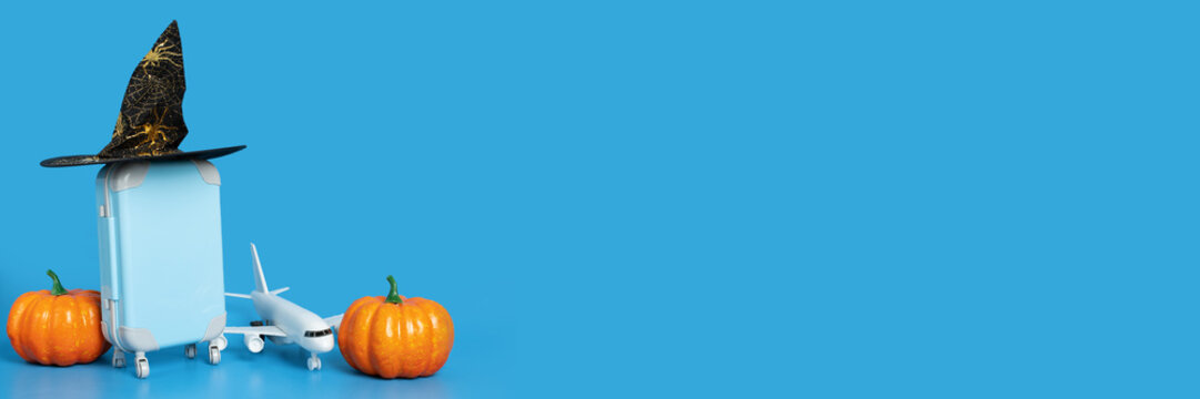 Halloween flight sale, airplane tickets, international flights, travel and trips, plane and luggage in a halloween hat with pumpkins on a blue background with copy space,holidays and vacations