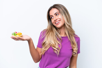 Young pretty Uruguayan woman holding a tartlet isolated on white background with happy expression