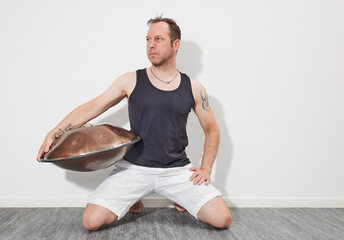 Man sitting on floor playing handpan