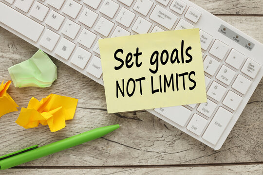 set goals not limits text on yellow sticker on white keyboard. working table