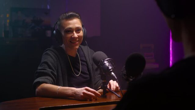 Androgyne girl is a guest on the podcast. A lesbian woman talks to a journalist, laughs and is surprised. They discuss psychology and LGBT issues on a radio show. Female butch is talking to a DJ.