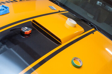 Installation (gluing, applying) of black strips decal of glossy foil on a yellow classic sports car...