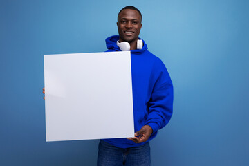 25 year old young american man shows a paper poster with a mockup for advertising on the background...