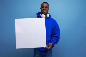 25 year old young american man shows a paper poster with a mockup for advertising on the background with copy space