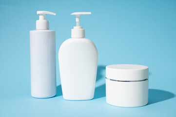 Commercial, brand packaging mockup. White blank bottles and jars for cosmetic beauty products, isolated on blue backdrop