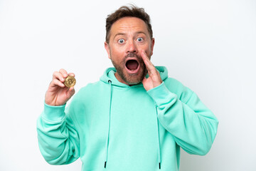 Middle age man holding a Bitcoin over isolated background with surprise and shocked facial expression