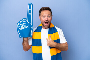 Middle age caucasian sports fan man isolated on blue background with surprise facial expression