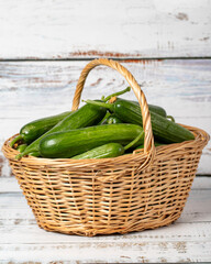 Fresh cucumber in a wicker basket over wooden background. Cucumber harvest season concept. Vegetables for a healthy diet. Close up