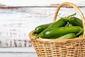 Fresh cucumber in a wicker basket over wooden background. Cucumber harvest season concept. Vegetables for a healthy diet. Copy space. Empty space for text