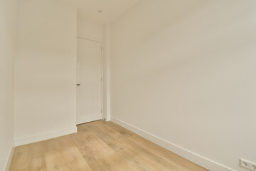 an empty room with white walls and wood flooring on the right, there is a door that leads to another room
