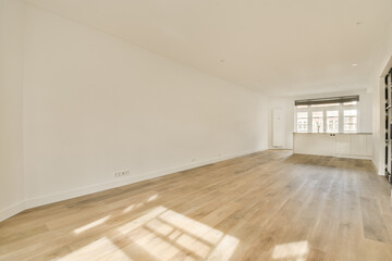 an empty living room with wood flooring and white walls on either side of the room, there is a large window in the