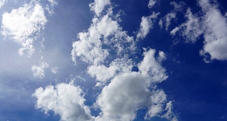 A blue sky background with cumulus white clouds in the sky then soft sun flare light.