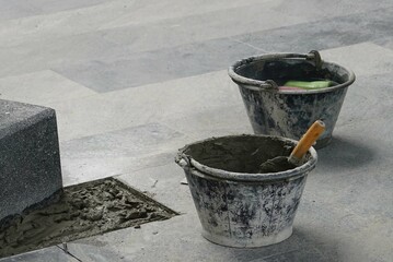 Naklejka premium A construction trowel and cement bucket on the floor to preparing work.