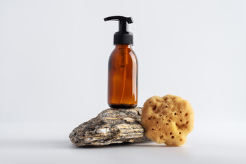 Mock up brown glass bottle and sea natural sponge on a stone podium
