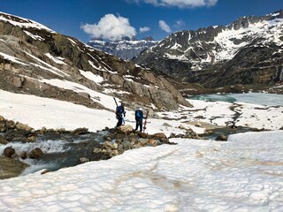 Fototapeta na wymiar Ski tourers have to jump over a stream. Susten Pass above Meiringen in the canton of Bern. Ski mountaineering. High quality photo