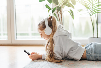 Little girl listening music lying on the floor
