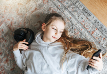 Little girl listening music lying on the floor