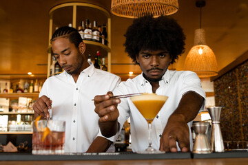 two latin bartenders with curly hair making cocktails