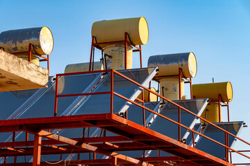 Naklejka premium solar panels and solar water heater boiler tanks on rooftop close up shot, blue sky background
