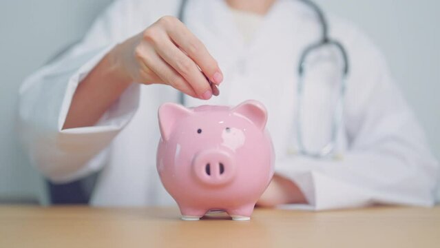 Doctor holding piggy bank and putting coin. and Healthcare cost, Money Saving, Health Insurance, Medical, Donation and Financial concepts