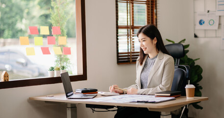 Beautiful woman using laptop and tablet while sitting at her working place. Concentrated at work..