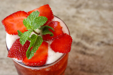Fresh strawberry ice tea and mint on wooden table, copy space. Cold summer drink.
