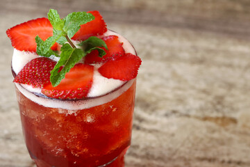 Fresh strawberry ice tea and mint on wooden table, copy space. Cold summer drink.