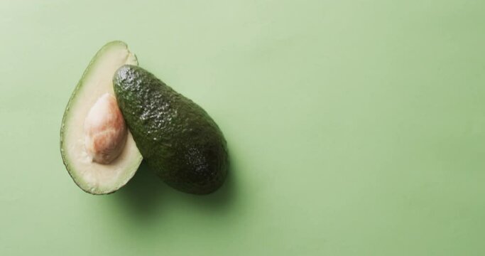 Video of sliced avocado with copy space over green background