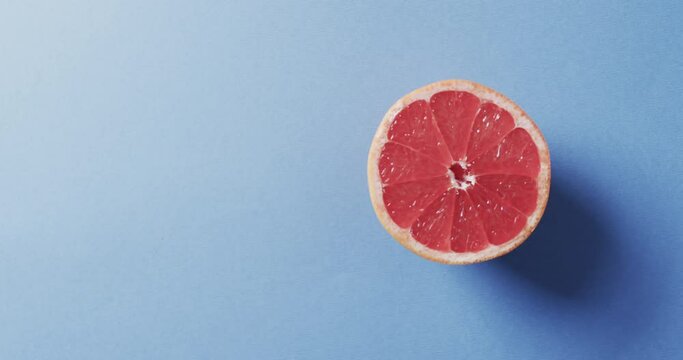 Video of sliced red grapefruit with copy space over blue background