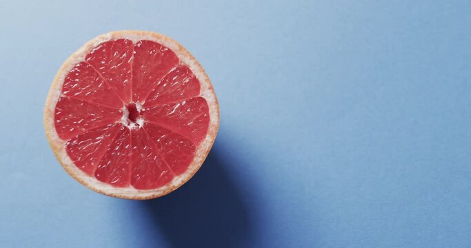 Video of sliced red grapefruit with copy space over blue background