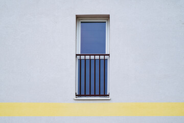 Façade d'un immeuble avec un mur blanc et grande fenêtre noire