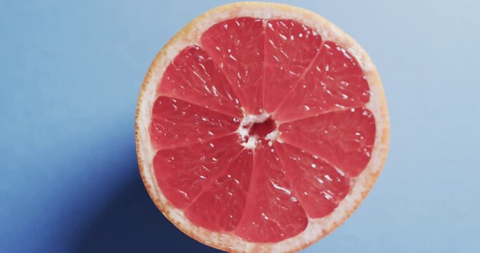 Video of sliced red grapefruit with copy space over blue background
